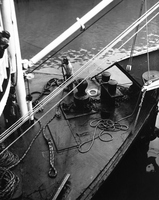 Alone on the foredeck, a hand coils lines under the watchful eye of the mate and passengers.