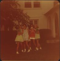 Four sorority sisters dressed in baby doll dresses and holding lollipops