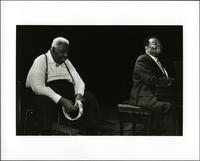 Jay McShann playing piano with unidentified man singing and holding a tambourine