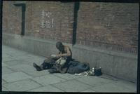 Hiller 04-010: Shirtless man sitting against a brick wall, head bent