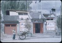 Hiller 08-019: Person supporting a rickshaw cart outside of a restaurant