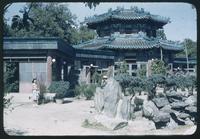 Hiller 08-056: Elaborate, colorful building with a woman and garden out front