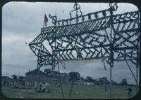 Hiller 11-028: Tall, wooden structure covered in foliage, in a grassy field, Festivals