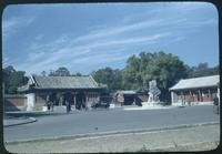 Hiller 08-117: Street with a statue and red and white buildings, Peiping